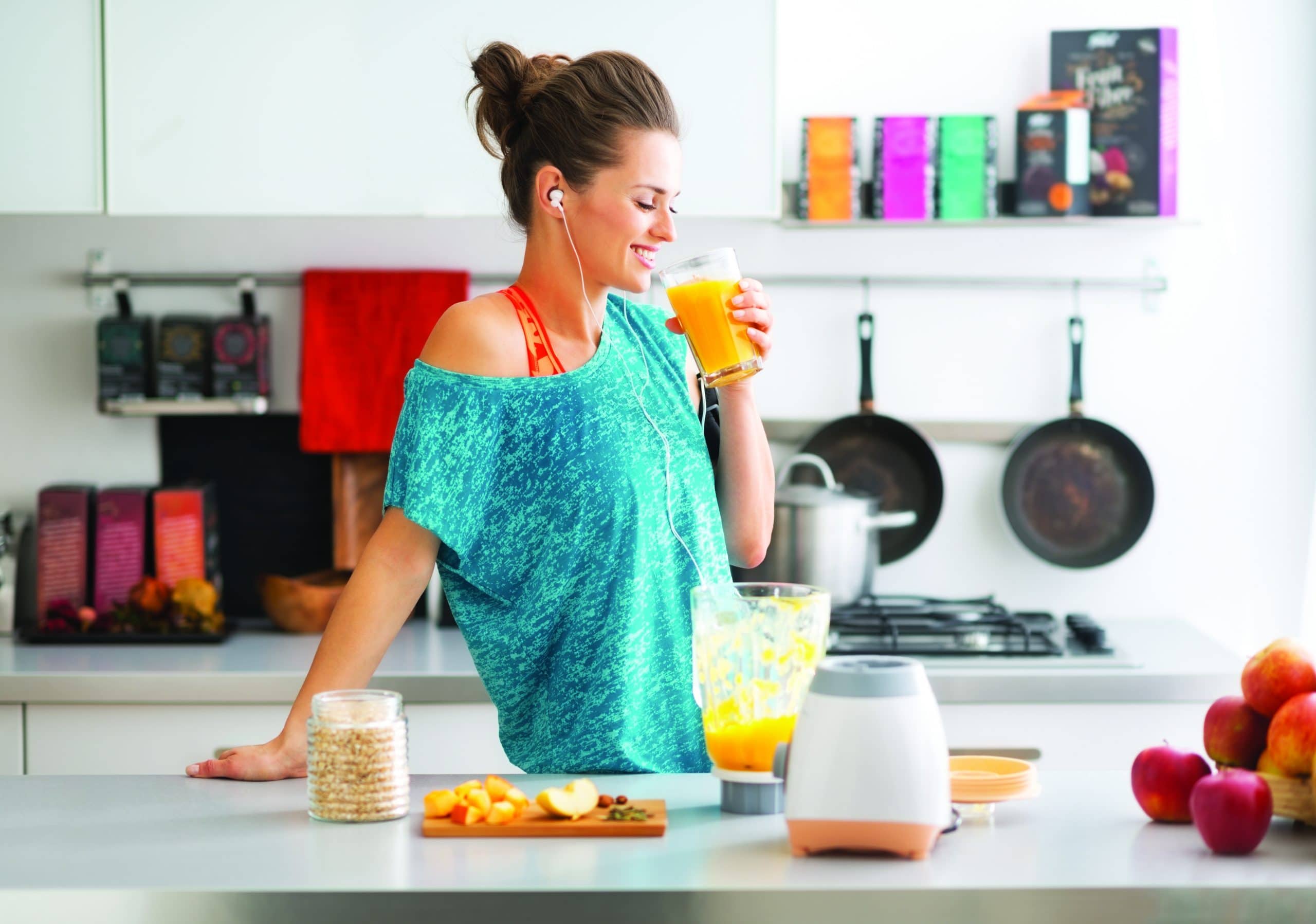 Happy fitness young woman drinking pumpkin smoothie in kitchen