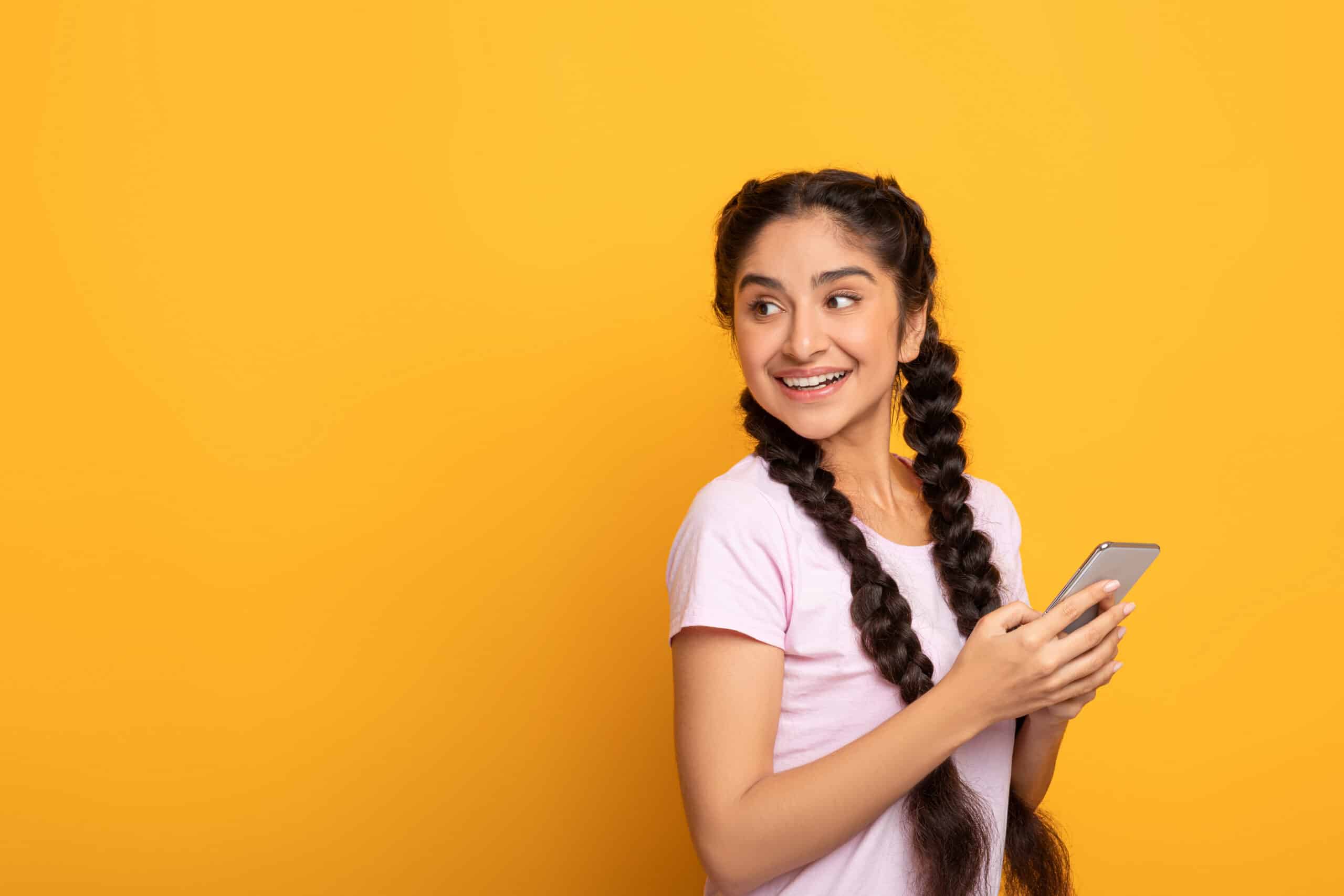 Indian woman using smart phone isolated on yellow background