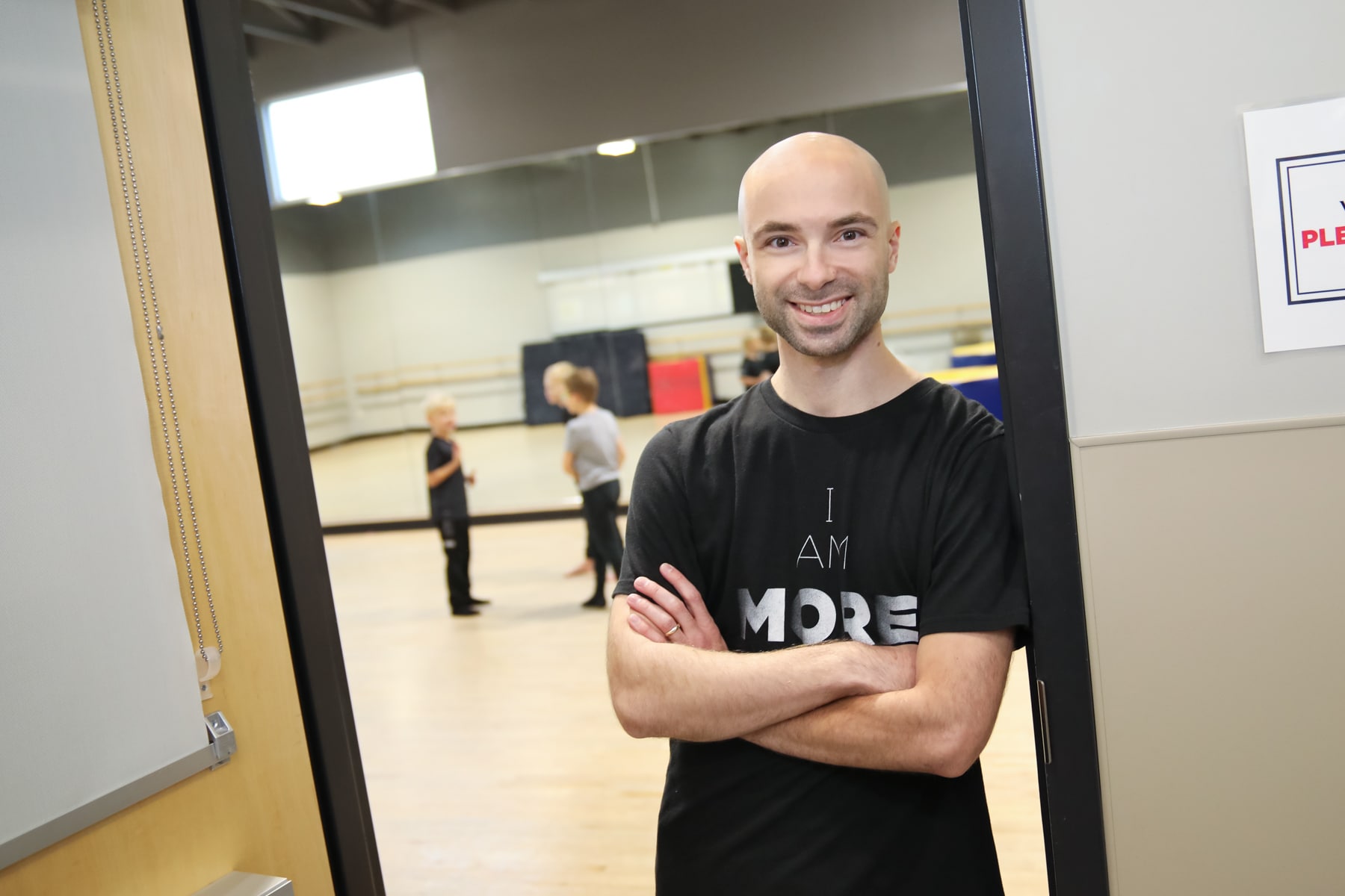 Male dance teacher standing in doorway smiling