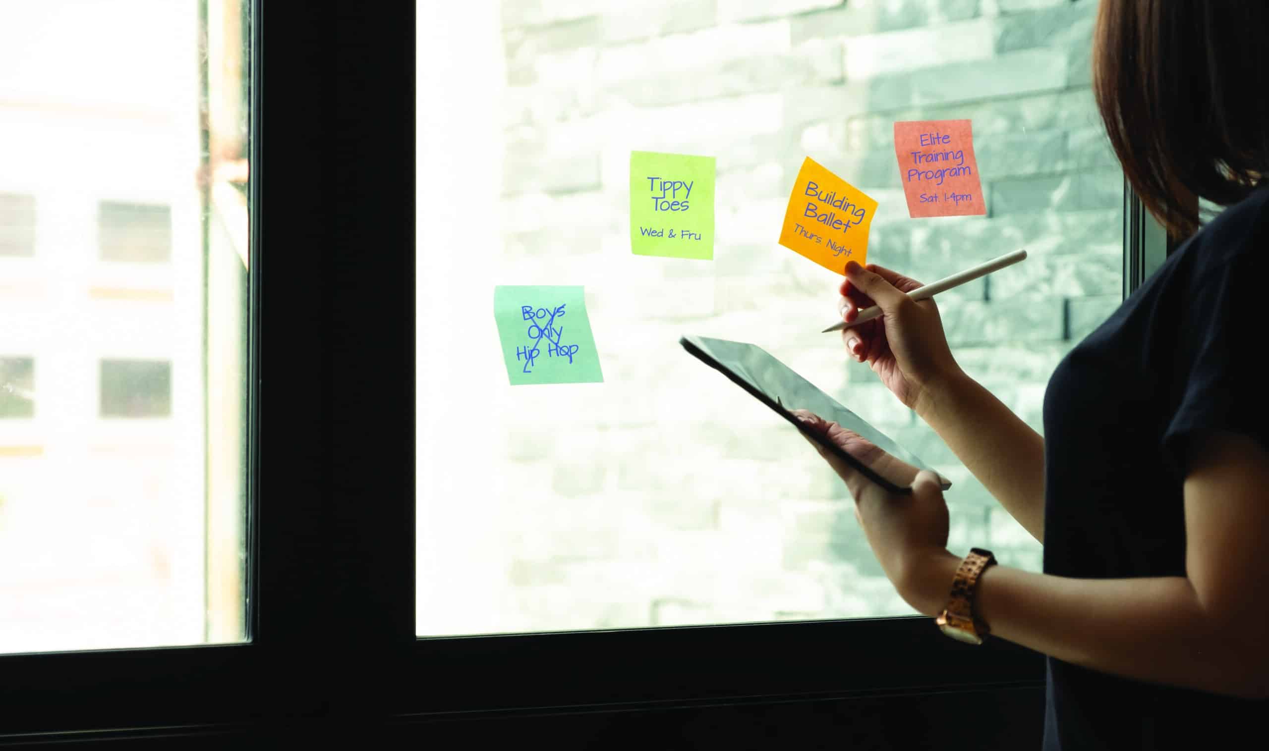 business woman using tablet during post it notes idea discussing and planning in glass wall at meeting room business concept